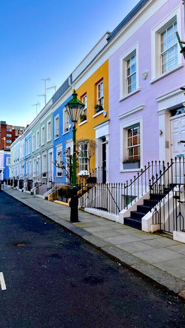 View of a street scene outside a three-storey brick building with large glass windows and white decorative window arches, showing a residential and commercial façade. The pavement in front of the bui